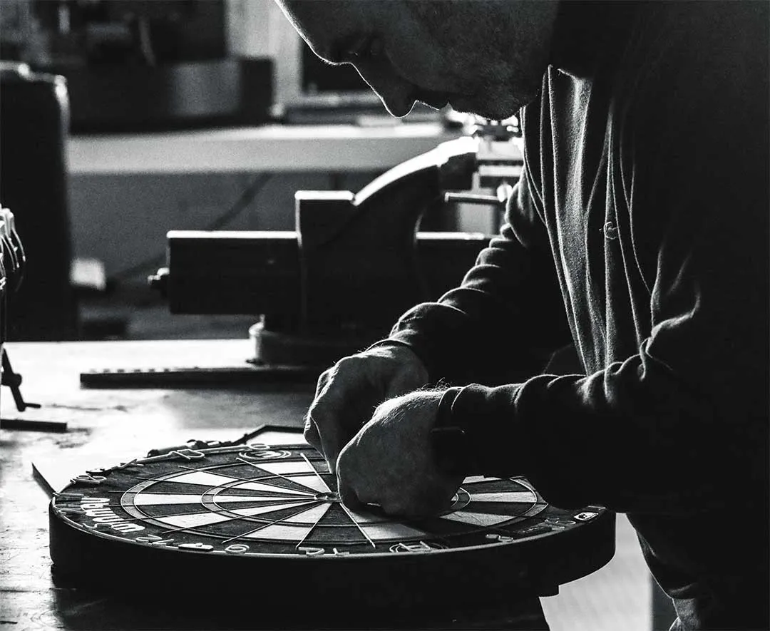 A craftsman inspecting a bristle dartboard at the workbench