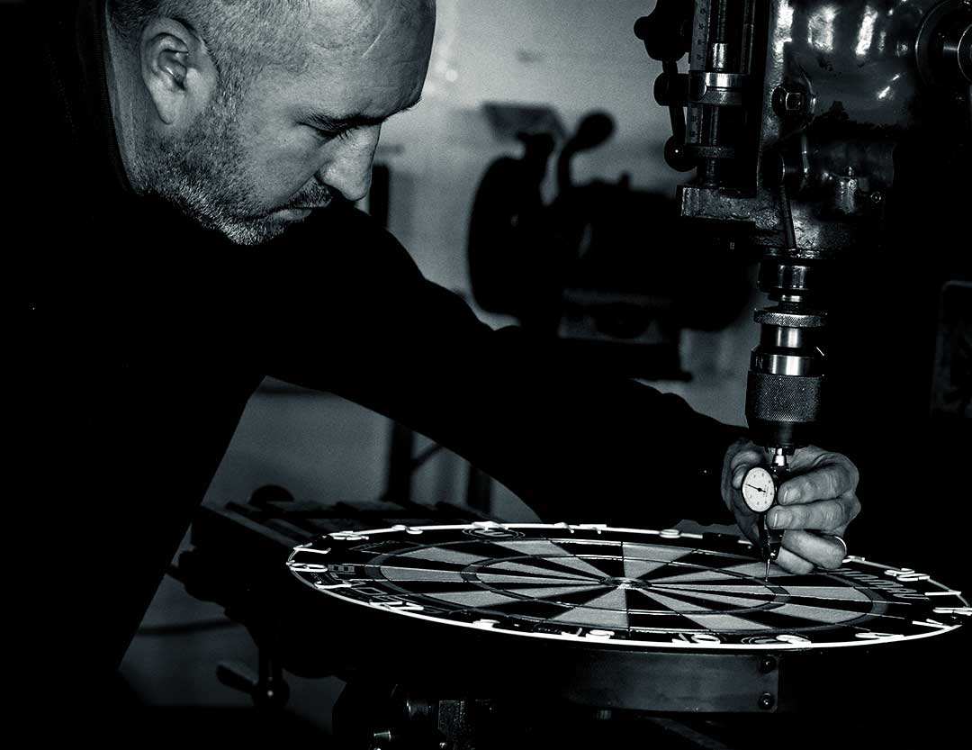 An engineer measuring a dartboard with a precision dial gauge