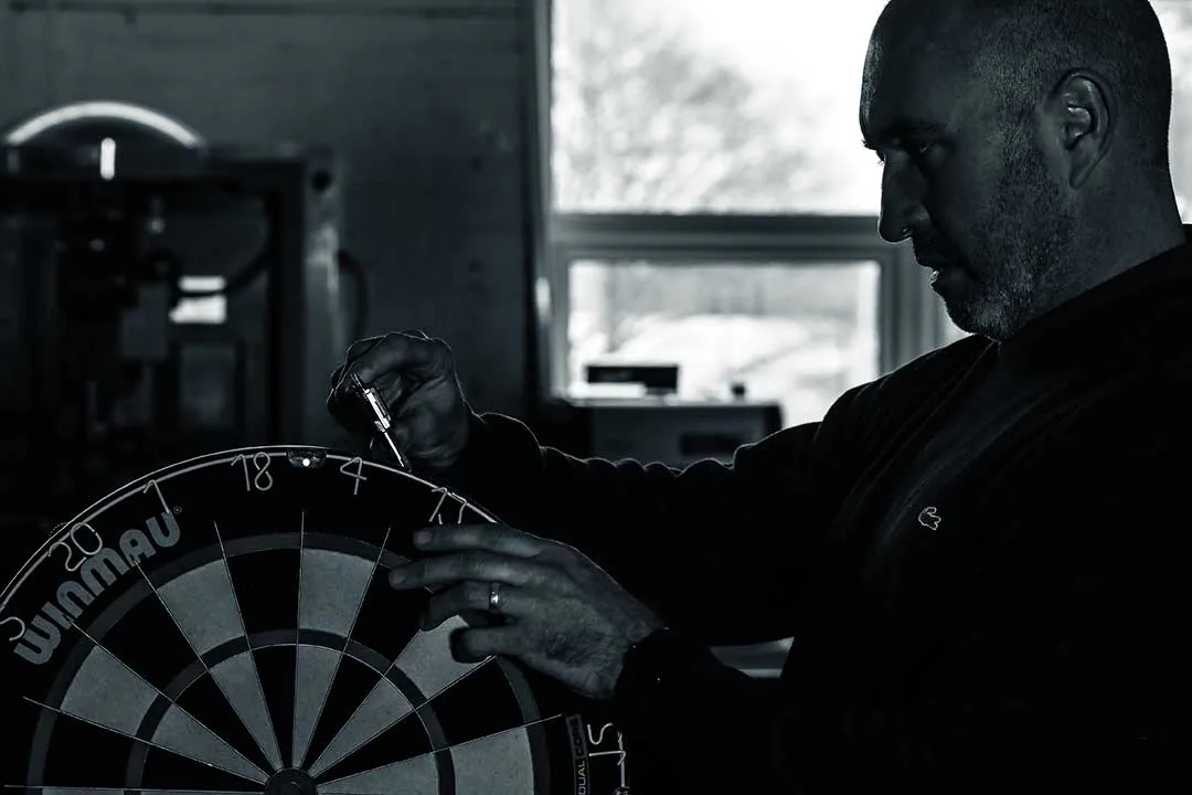 A craftsman examining the wiring of a Winmau dartboard