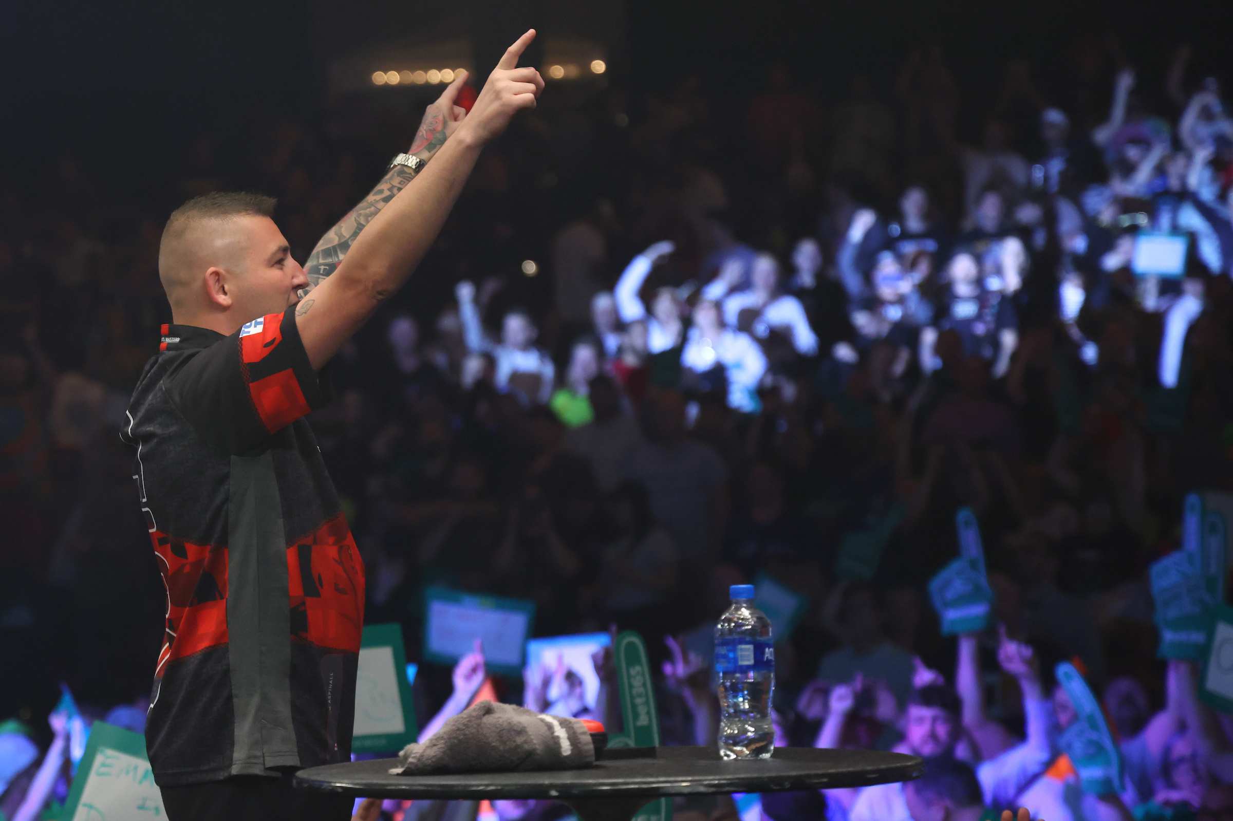 A player celebrating on stage in front of a packed arena
